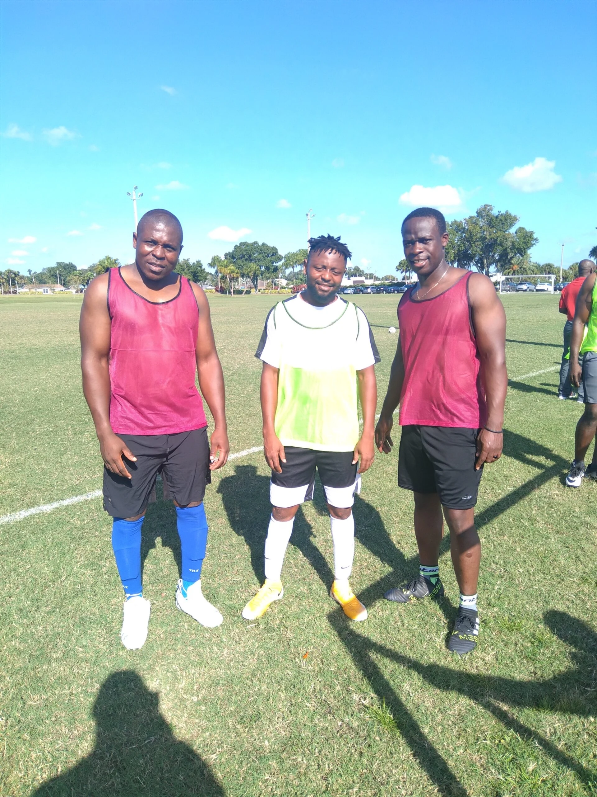 Three players in training bibs posing on the field