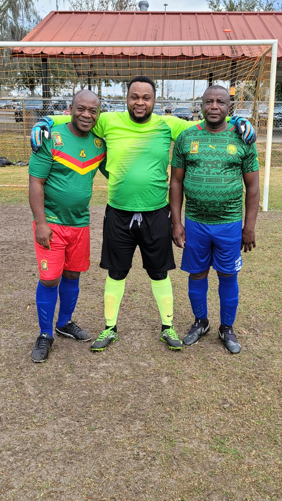 Three players posing beside the goal