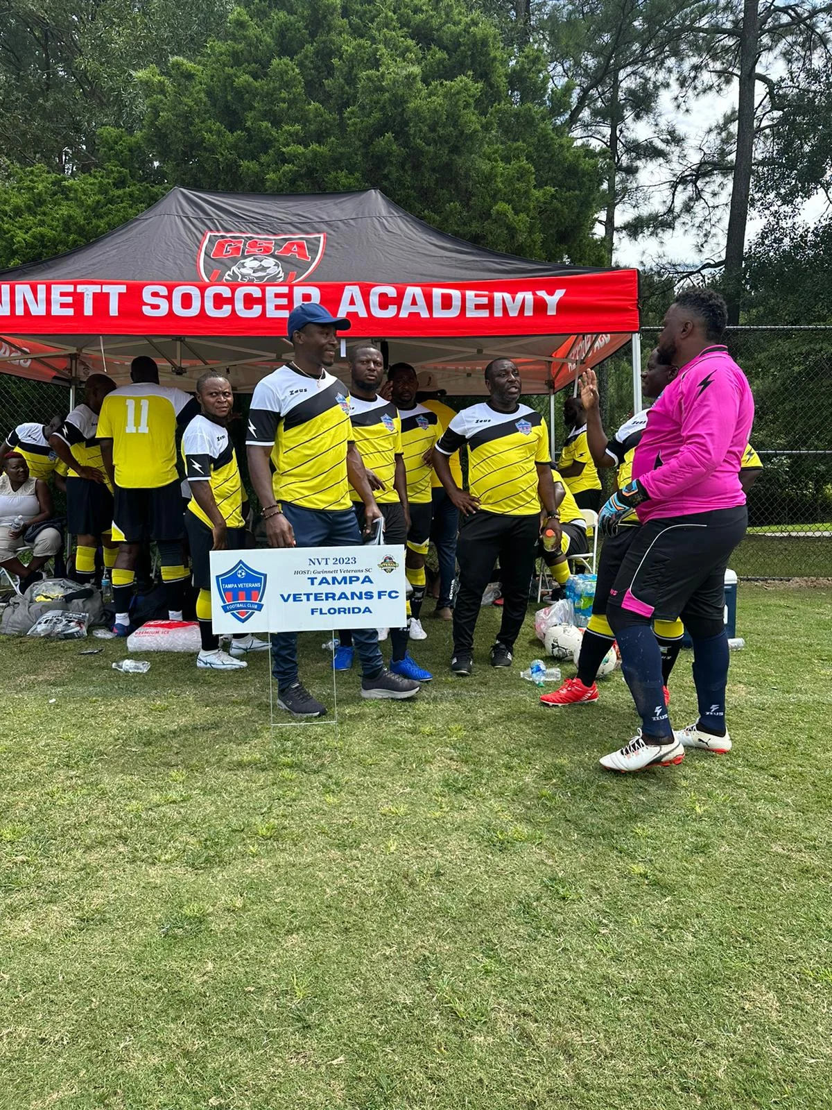 Club members gathered beside a soccer academy canopy