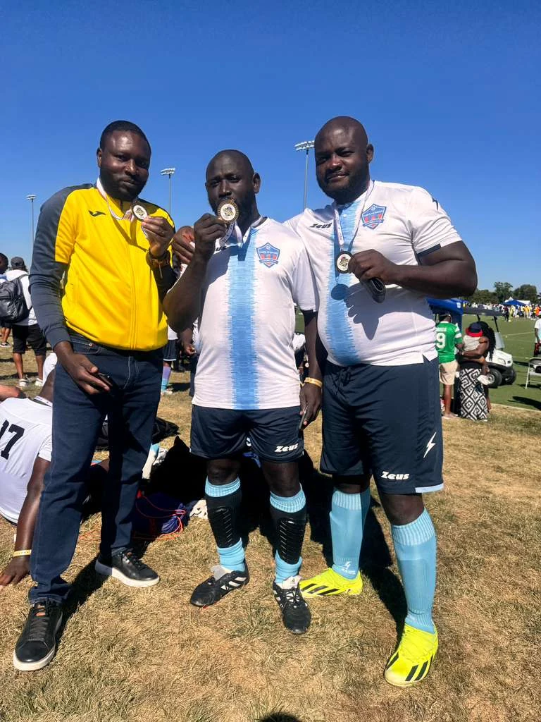 Three football players posing beside the field